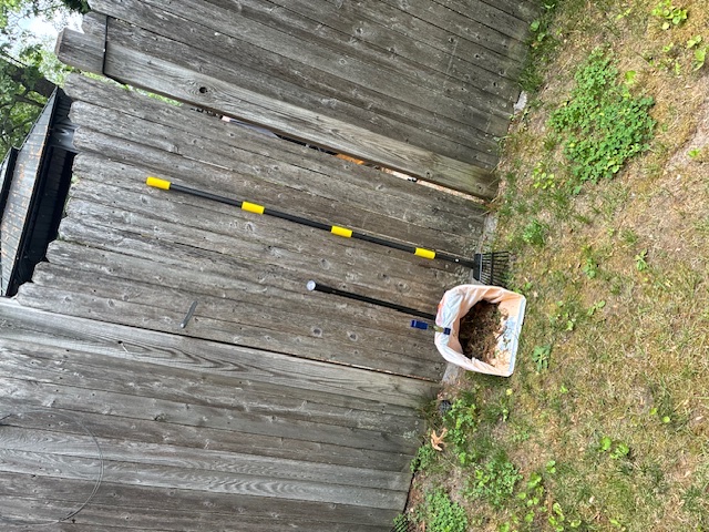 Cabral's pooper scooper tools by a wooden fence