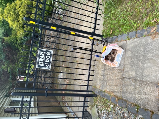Cabral's pickup bag and rake near a beware of dog gate