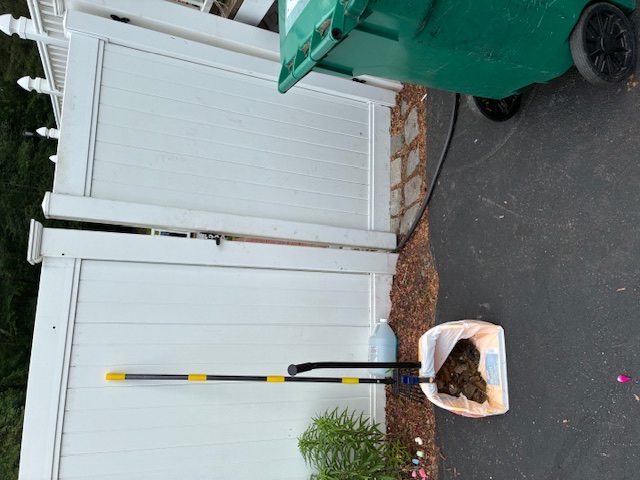 Cabral's cleanup tools beside a white fence and driveway